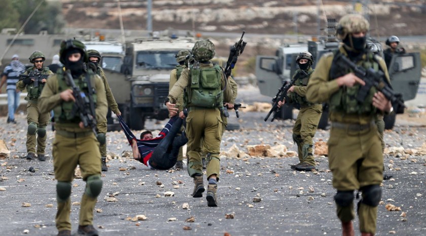 Israeli soldiers detain a wounded Palestinian protester during clashes near the Jewish settlement of Bet El